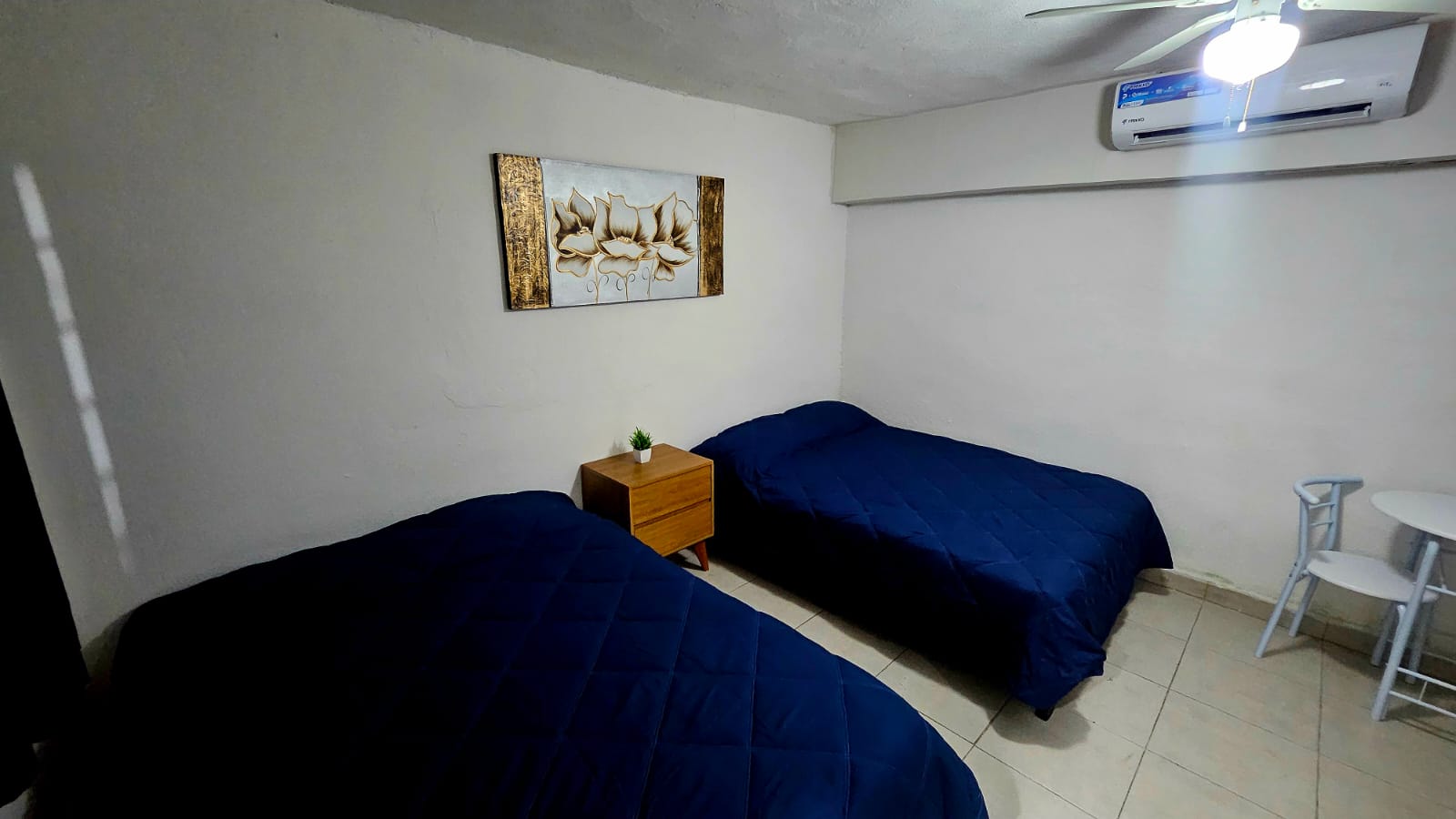 El Loft donde se ven las camas, el buró, el cuadro, el aire acondicionado y la mesa