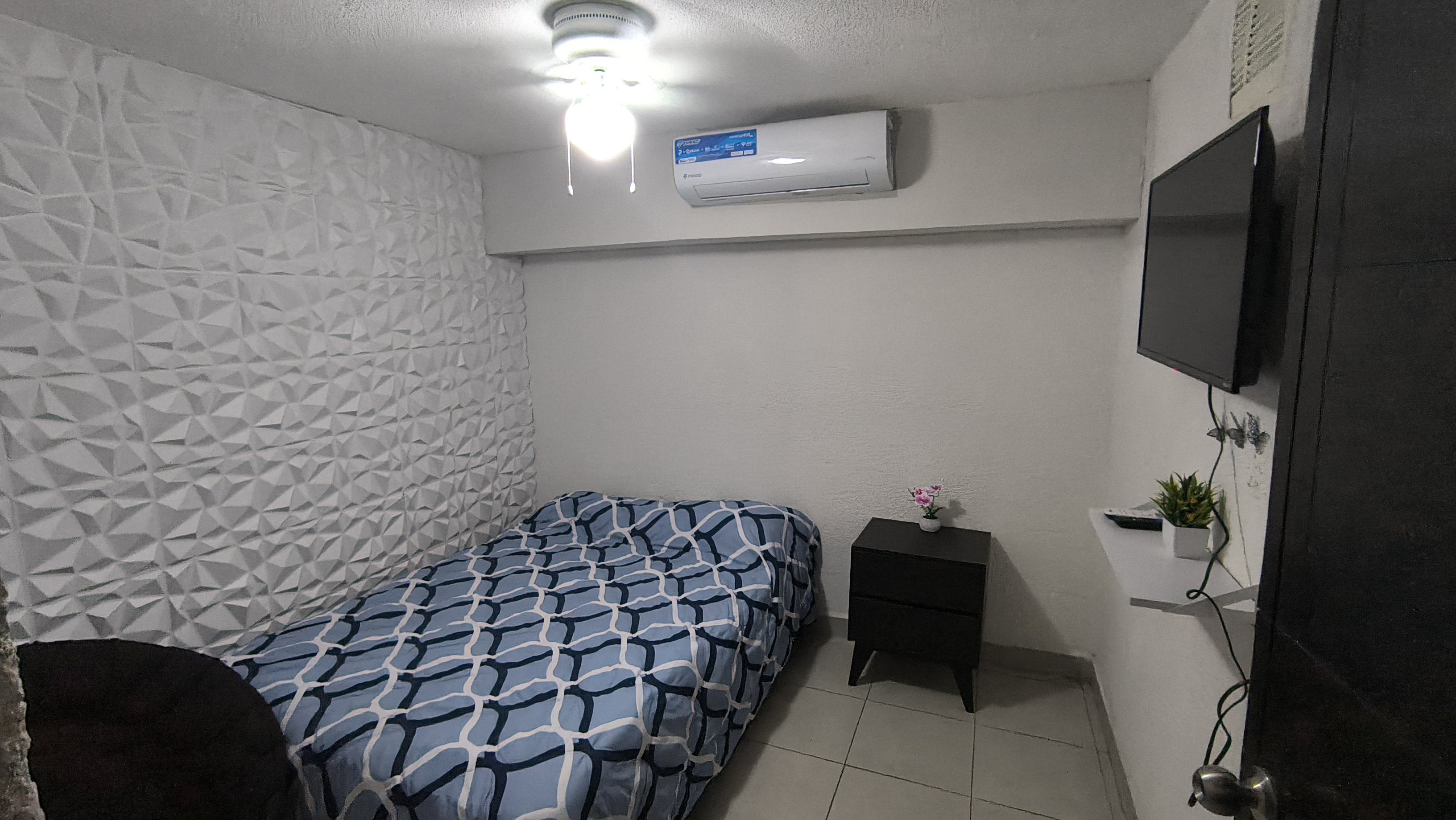 El cuarto 1 del Loft donde se ve la cama, el buró, la tele, el clima y el ventilador